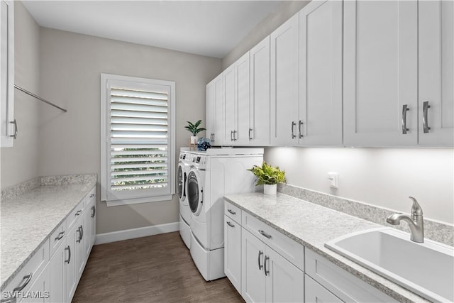 laundry room featuring separate washer and dryer, cabinet space, dark wood finished floors, and baseboards