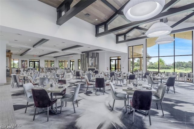 dining room with beam ceiling, a towering ceiling, plenty of natural light, and recessed lighting