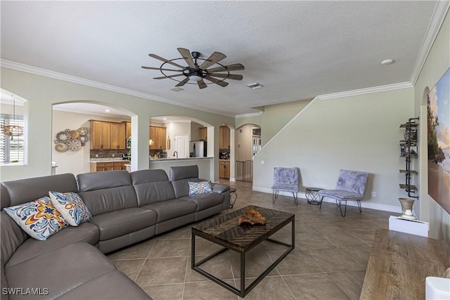 living room featuring baseboards, visible vents, ceiling fan, and ornamental molding