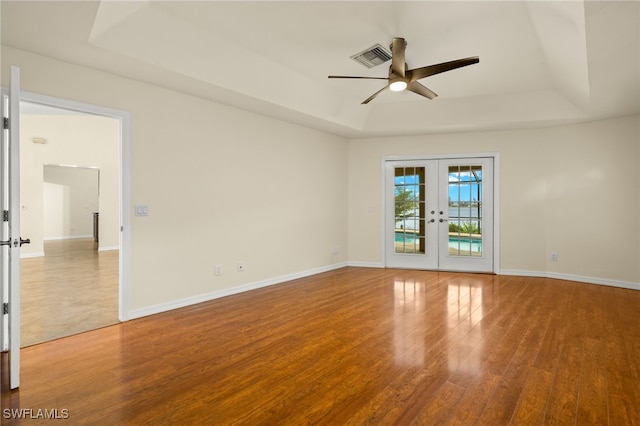 920 SW 4th Pl, Cape Coral, FL 33991 - spare room featuring a ceiling fan, wood finished floors, baseboards, a tray ceiling, and french doors