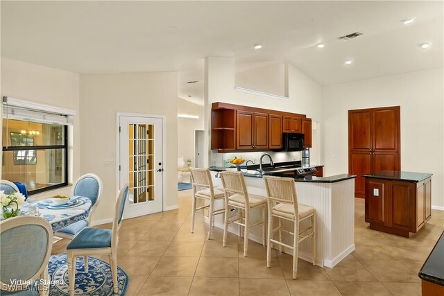 920 SW 4th Pl, Cape Coral, FL 33991 - kitchen with a breakfast bar area, a peninsula, open shelves, black microwave, and dark countertops