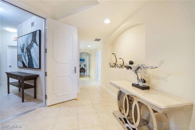 corridor with light tile patterned floors, visible vents, baseboards, recessed lighting, and arched walkways