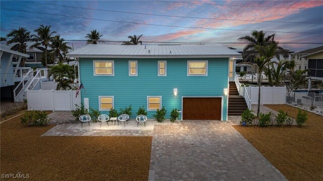 360 Bayland Rd, Fort Myers Beach, FL 33931 - view of front facade with stairway, fence, metal roof, decorative driveway, and a garage
