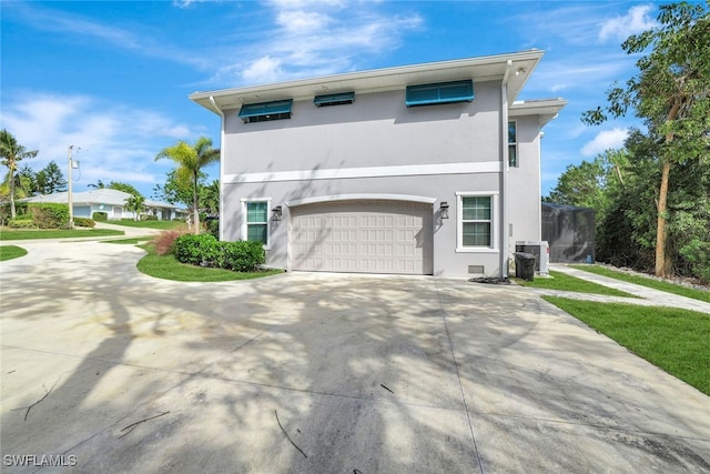 view of front of property with stucco siding, central AC, driveway, and a garage