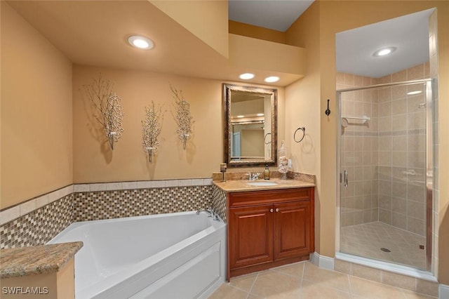 bathroom featuring tile patterned floors, a stall shower, a bath, and vanity
