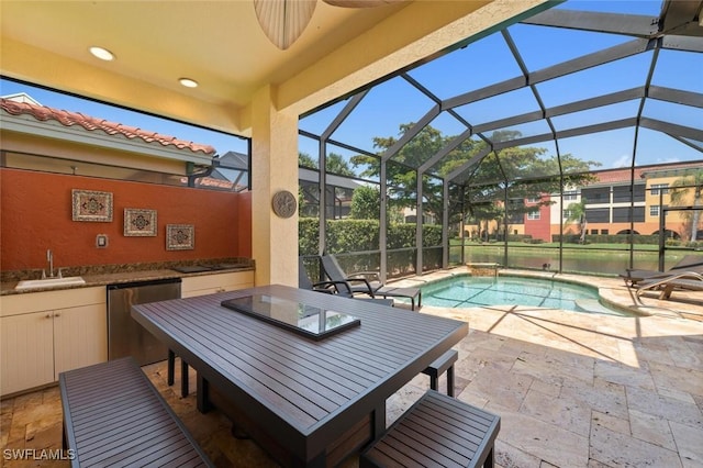 pool with a sink, a patio, glass enclosure, outdoor dining area, and an outdoor kitchen