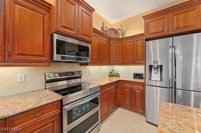 kitchen with light tile patterned flooring, stainless steel appliances, tasteful backsplash, and light stone countertops
