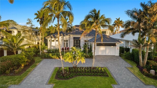 mediterranean / spanish-style home with a front lawn, stucco siding, french doors, decorative driveway, and a garage