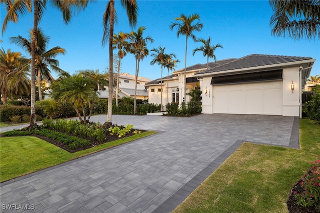 1955 Tarpon Rd, Naples, FL 34102 - view of front of house featuring decorative driveway, a garage, stucco siding, and a front lawn