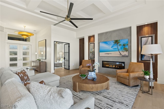 living room featuring wood finished floors, ceiling fan, and coffered ceiling