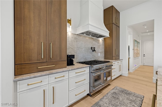 1955 Tarpon Rd, Naples, FL 34102 - kitchen featuring double oven range, custom exhaust hood, light wood-style flooring, white cabinetry, and decorative backsplash