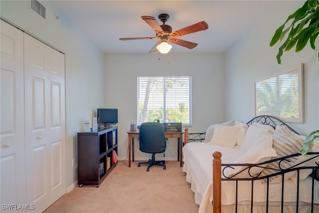 bedroom with a closet, light carpet, baseboards, visible vents, and ceiling fan