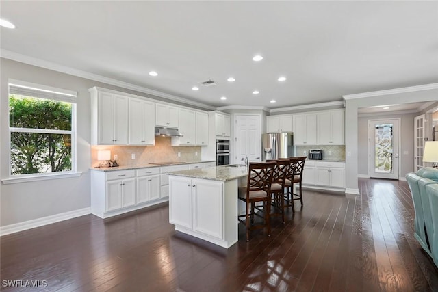 kitchen with under cabinet range hood, stainless steel appliances, ornamental molding, visible vents, and recessed lighting