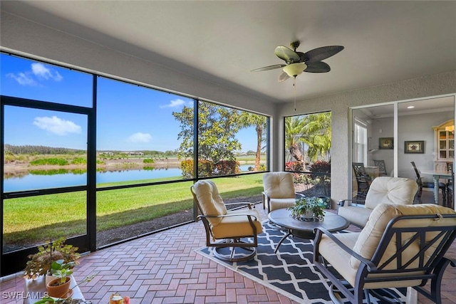 sunroom with a ceiling fan and a water view
