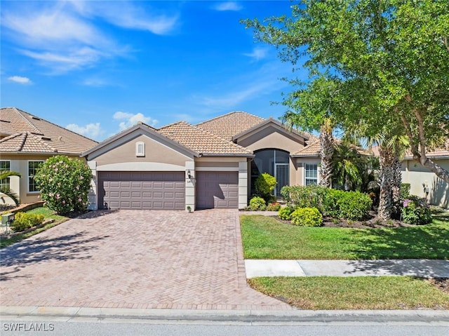 ranch-style house with a garage, stucco siding, a tiled roof, and decorative driveway
