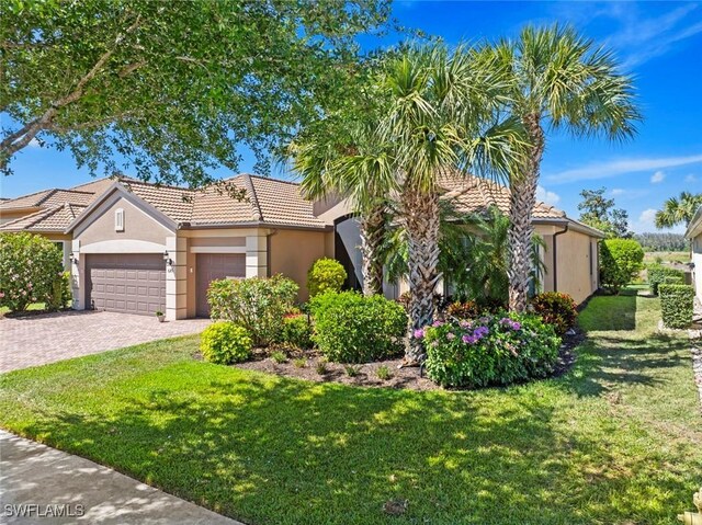 view of front of house featuring decorative driveway, a front lawn, a tiled roof, a garage, and stucco siding