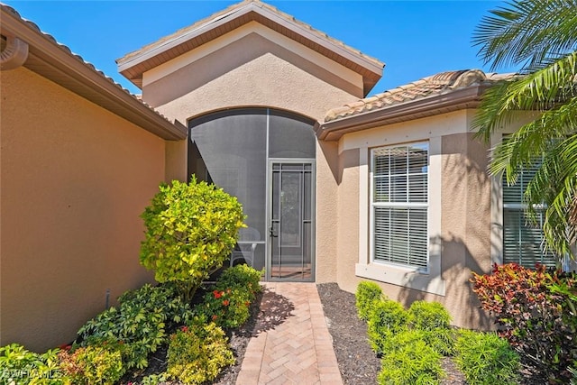 property entrance featuring a tile roof and stucco siding