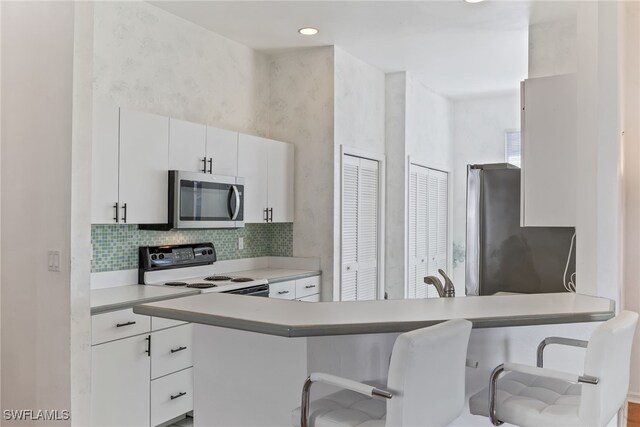 3895 Sabal Springs Blvd, North Fort Myers, FL 33917 - kitchen with white cabinetry, a breakfast bar, light countertops, stainless steel appliances, and decorative backsplash