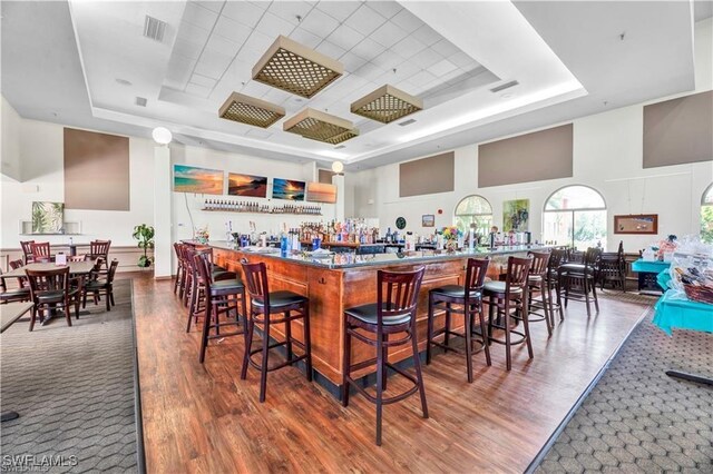 3895 Sabal Springs Blvd, North Fort Myers, FL 33917 - bar with visible vents, a tray ceiling, wood finished floors, and a towering ceiling