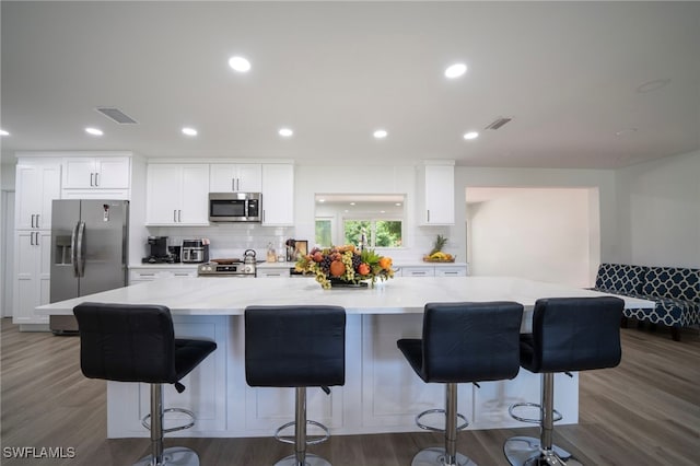 2333 Westwood Rd, North Fort Myers, FL 33917 - kitchen featuring appliances with stainless steel finishes, white cabinets, tasteful backsplash, a large island with sink, and dark wood-type flooring
