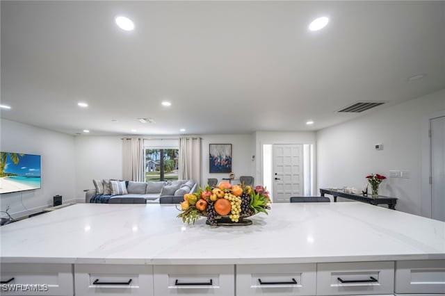 2333 Westwood Rd, North Fort Myers, FL 33917 - kitchen with light stone countertops, white cabinetry, open floor plan, recessed lighting, and a center island