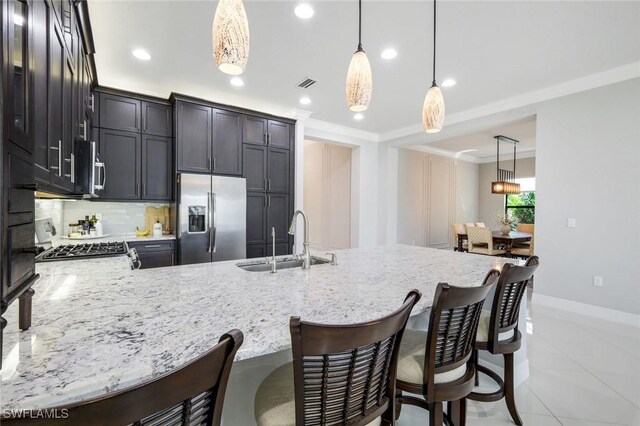 4318 Aurora St, Naples, FL 34119 - kitchen with stainless steel appliances, a sink, a peninsula, backsplash, and light stone countertops