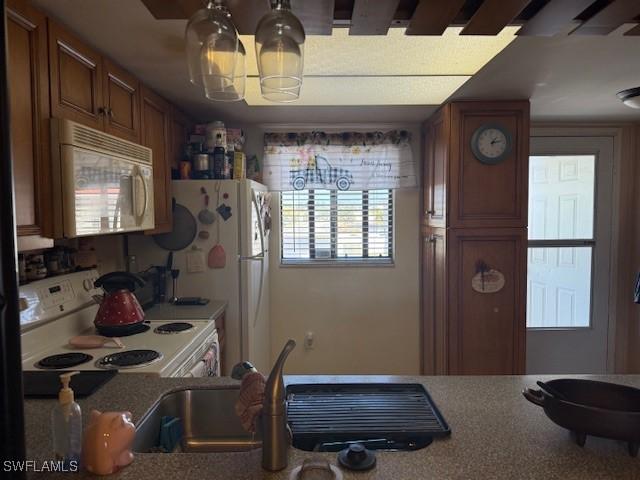 kitchen featuring a sink, brown cabinets, and white appliances