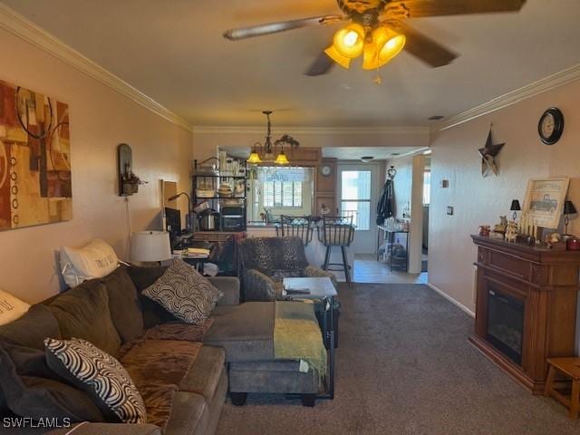 carpeted living area with baseboards, crown molding, a glass covered fireplace, and a ceiling fan