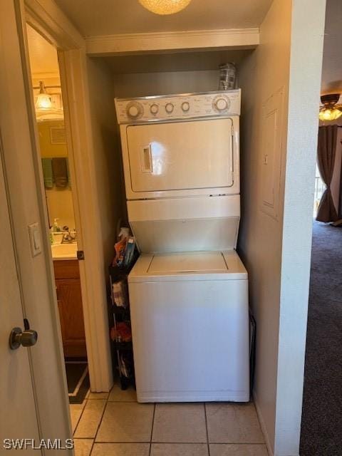 laundry room featuring light tile patterned flooring, stacked washer / drying machine, and laundry area