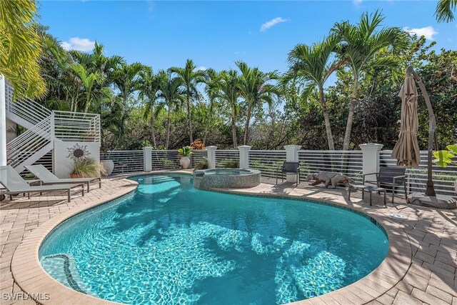 view of pool featuring a pool with connected hot tub, stairway, and a patio area