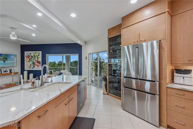 kitchen featuring recessed lighting, light tile patterned floors, a sink, light stone counters, and appliances with stainless steel finishes