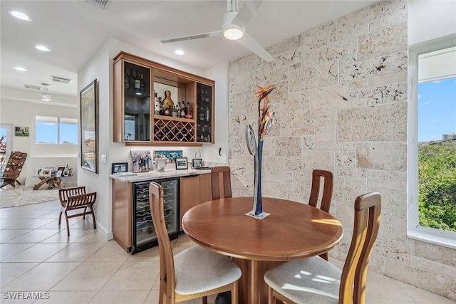 dining space featuring a healthy amount of sunlight, light tile patterned floors, wine cooler, a ceiling fan, and indoor wet bar