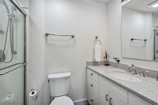 full bathroom featuring a stall shower, toilet, and vanity