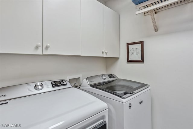 clothes washing area with washer and dryer and cabinet space