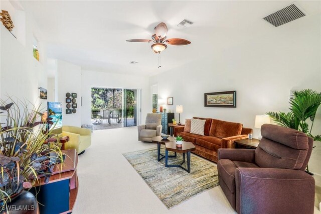 living room with visible vents, a ceiling fan, and carpet flooring