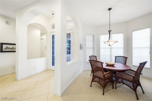 dining room featuring arched walkways, baseboards, and tile patterned flooring