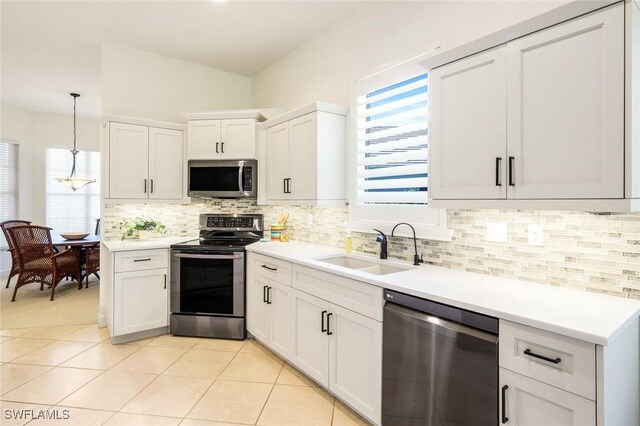 kitchen with pendant lighting, appliances with stainless steel finishes, light countertops, a sink, and decorative backsplash