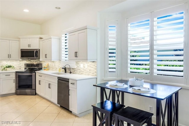 kitchen with tasteful backsplash, light tile patterned floors, light countertops, appliances with stainless steel finishes, and a sink