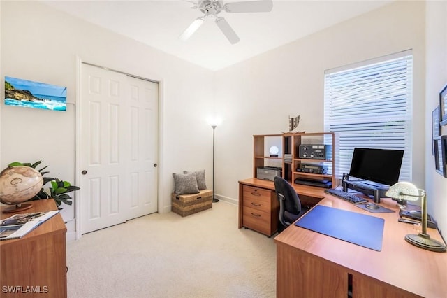 home office with a ceiling fan and light carpet