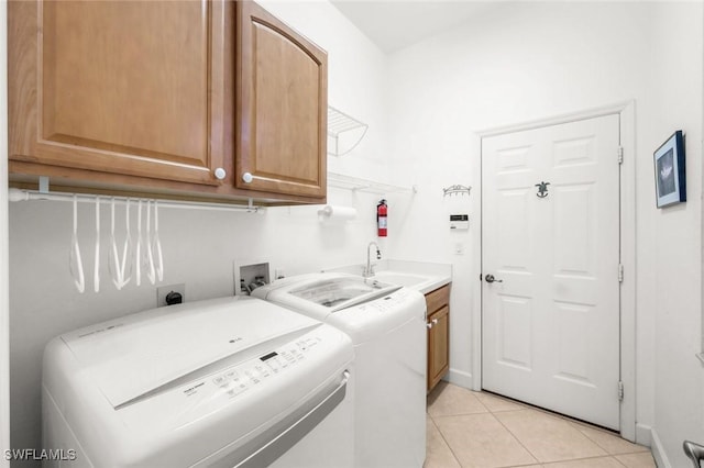 laundry area with light tile patterned floors, a sink, cabinet space, and washer and clothes dryer