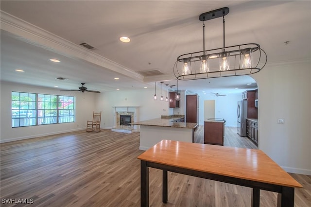 20587 Charing Cross Cir, Estero, FL 33928 - kitchen with freestanding refrigerator, a ceiling fan, crown molding, a fireplace with raised hearth, and a kitchen island