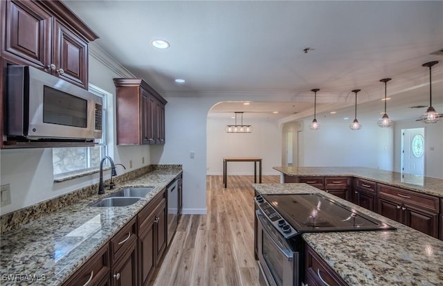 20587 Charing Cross Cir, Estero, FL 33928 - kitchen featuring appliances with stainless steel finishes, a sink, light wood-style flooring, hanging light fixtures, and arched walkways