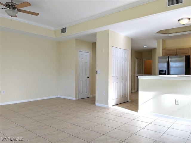spare room with a ceiling fan, visible vents, crown molding, and light tile patterned floors