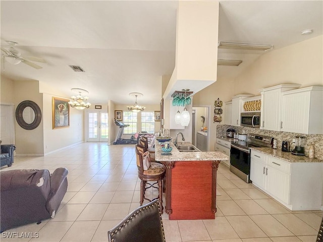 3911 9th St SW, Lehigh Acres, FL 33976 - kitchen with a kitchen breakfast bar, tasteful backsplash, open floor plan, stainless steel appliances, and light tile patterned flooring