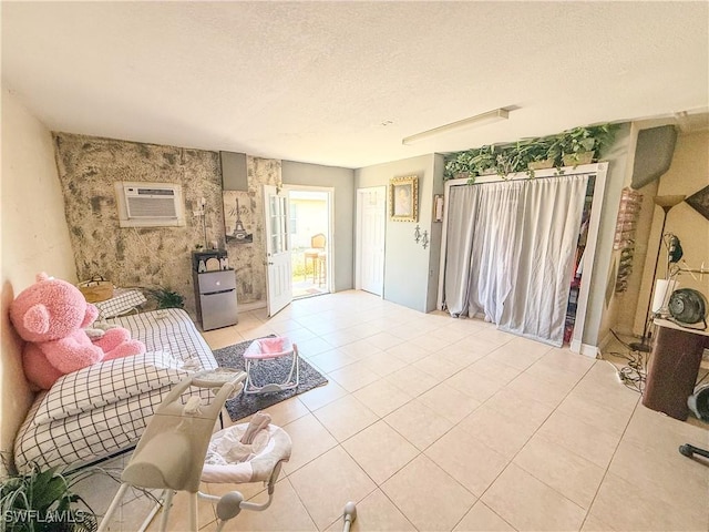 3911 9th St SW, Lehigh Acres, FL 33976 - living area with a textured ceiling, light tile patterned floors, an accent wall, and a wall mounted air conditioner