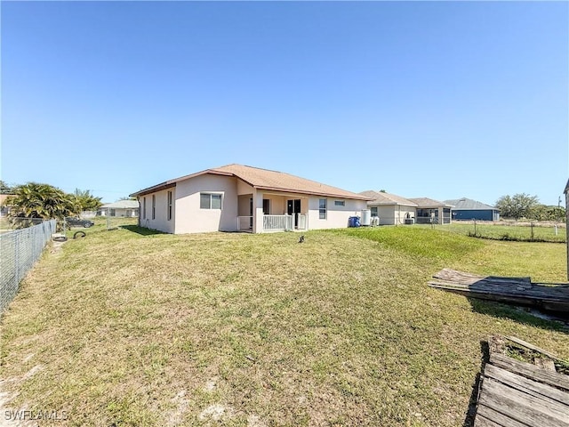 3911 9th St SW, Lehigh Acres, FL 33976 - back of house featuring a yard, fence, and stucco siding