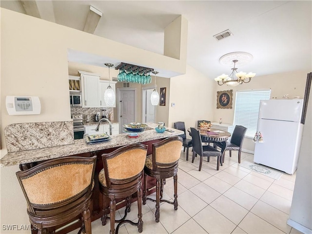 3911 9th St SW, Lehigh Acres, FL 33976 - dining space featuring a chandelier, visible vents, light tile patterned floors, and vaulted ceiling