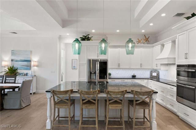 kitchen with crown molding, stainless steel appliances, premium range hood, backsplash, and visible vents