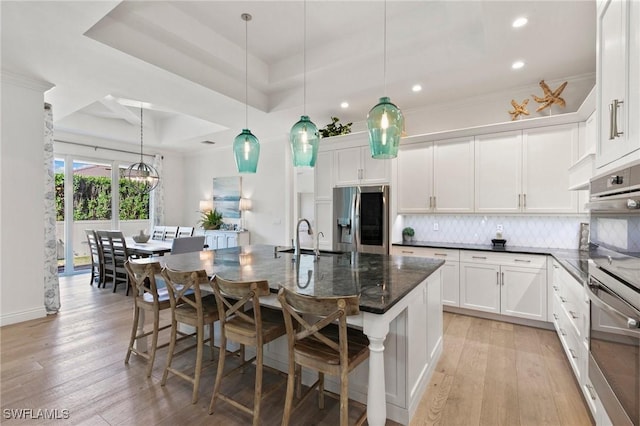 kitchen featuring light wood-style flooring, a sink, stainless steel fridge, tasteful backsplash, and recessed lighting