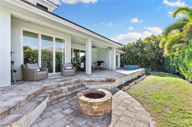 view of patio / terrace featuring fence, a ceiling fan, and a fire pit